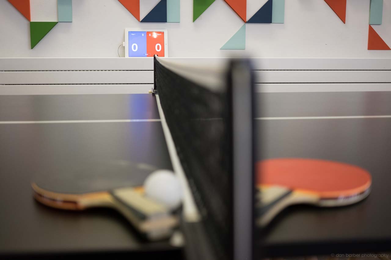 Photo of the ping pong table with paddles, and the scoreboard iPad behind it